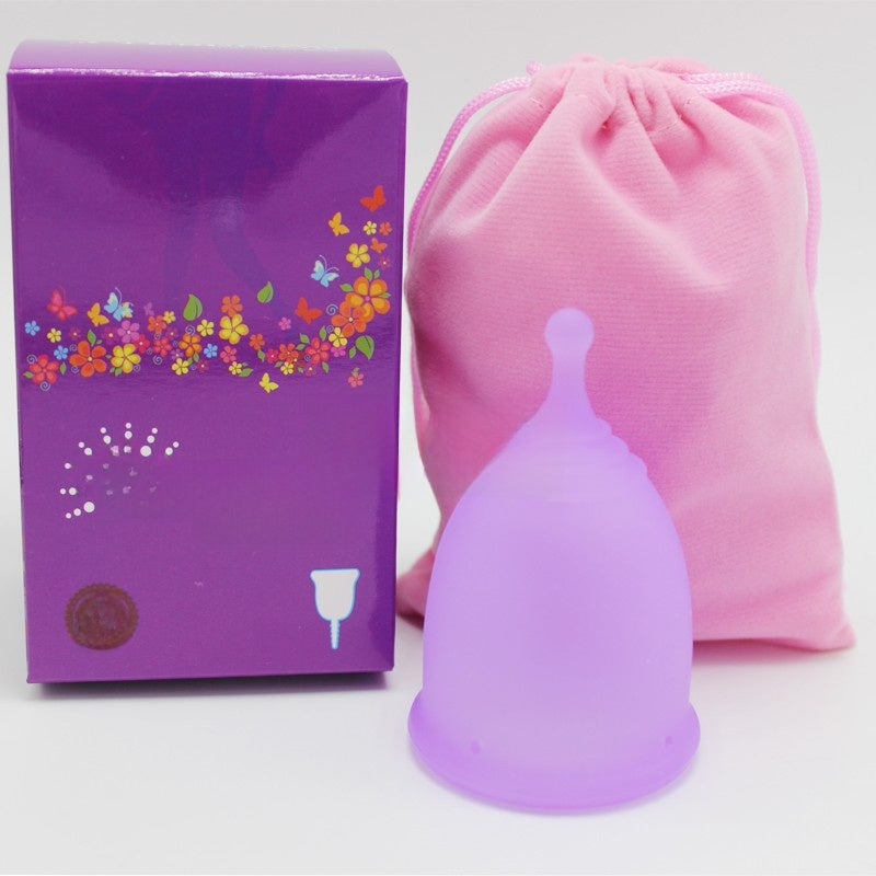 Purple menstrual cup with packaging and pink drawstring bag on a white background